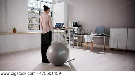 Woman Using Adjustable Height Standing Desk In Office For Good Posture