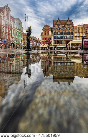 Wroclaw, Poland - July 2022: Wroclaw Market Square Old Tenement Houses Reflected In Small Puddle