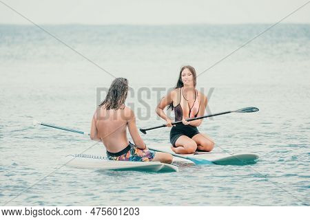 Sea Woman And Man On Sup. Silhouette Of Happy Young Woman And Man, Surfing On Sup Board, Confident P