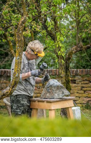 Sebastiano Da Po, Italy - April 12 2023: Woman Carving A Stone During An Outdoor Sculpture Lesson Or