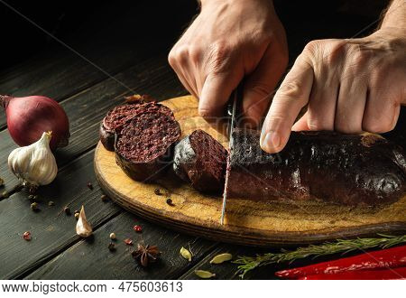 The Chef Cuts Blood Sausage With A Knife On A Cutting Board Before Serving For Lunch. National Dish 