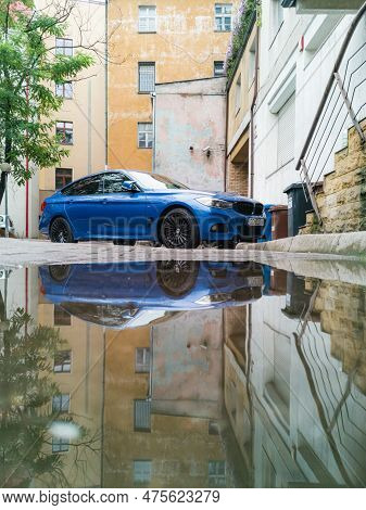 Wroclaw, Poland - August 2022: Blue Bmw Car Standing On Car Parking And Reflected In Small Puddle