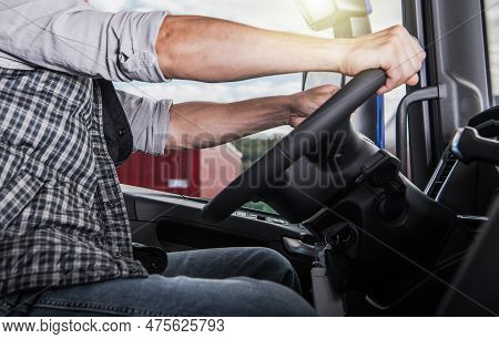 Professional Semi Truck Driver Behind The Tractor Wheel. Heavy Transportation Industry Concept.