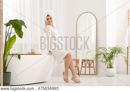 Beautiful Woman In Soft Robe Sitting On Tub In Bathroom