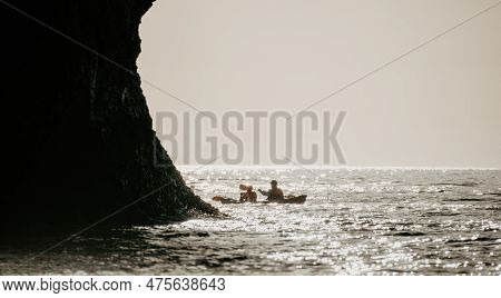 Happy Couple Kayaks In An Inflatable Kayak On The Sea At Sunset. Couple Kanoeing In The Sea Near The