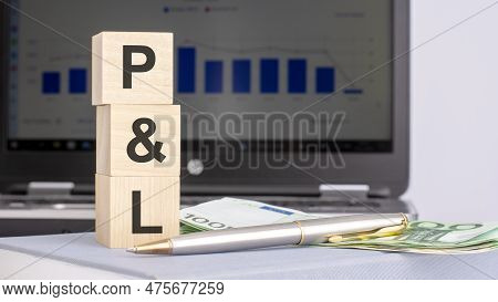 Close-up Of Wooden Blocks With The Word P And L And Banknotes On The Background Of A Laptop