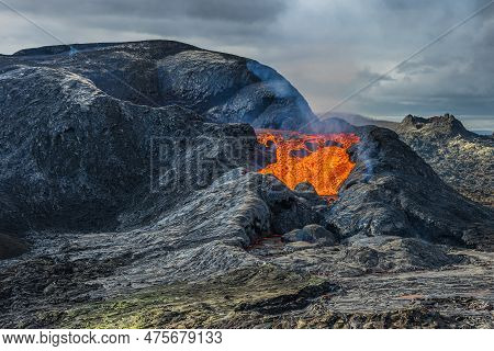 Lava Flows From A Volcanic Crater. Hot Reddish Liquid Magma From The Volcano. Volcanic Landscape On 