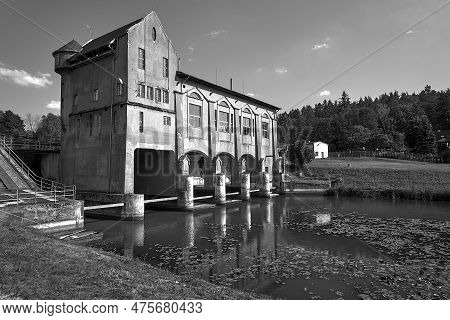 The River And The Building Of A Historic Hydroelectric Power Plant In Bledzew In Poland, Monochrome