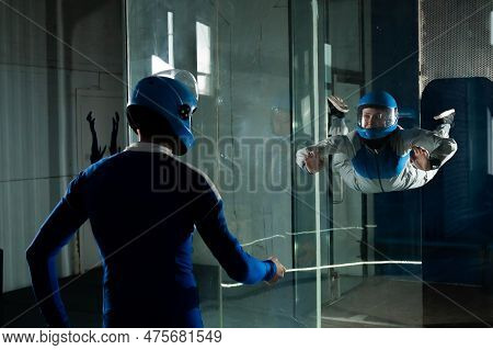 A Male Instructor Teaches A Woman How To Fly In A Wind Tunnel. Free Fall Simulator.