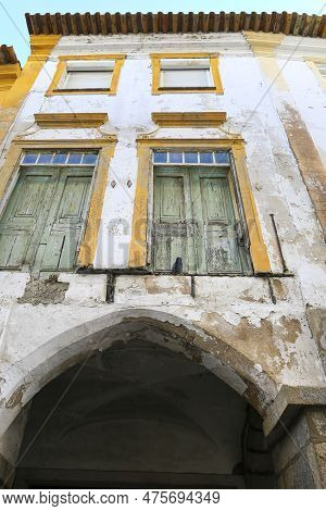 Old House With White Chipped Facade And Green Wooden Windows In Evora Town, Portugal