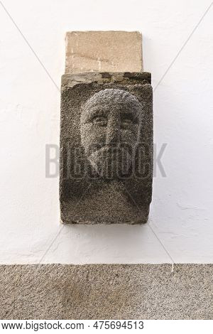 Ancient Carved Stone Face On Facade In The Old Town Of Evora, Alentejo, Portugal