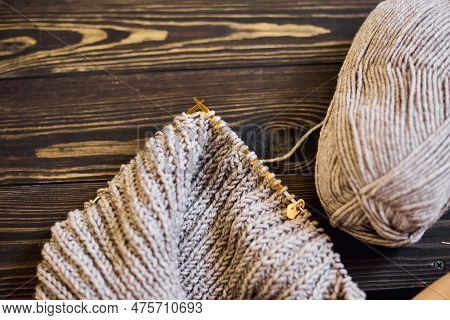 Knitted Sweater With A Knitting Needles. Close Up Photo On Grey Background With Copy Space. Knitting