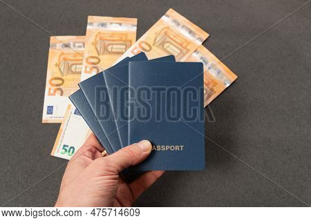 Four Blu-covered Passports In Man Hands On Euro Cash Background. Passport With Blank Cover On Money 