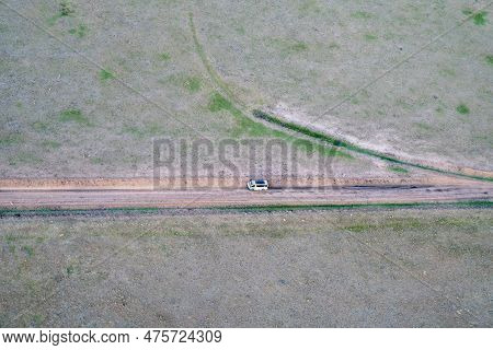 Very High Aerial View Of The Masaai Mara Reserve In Kenya During Sunrise. Safari Van Drives On The D