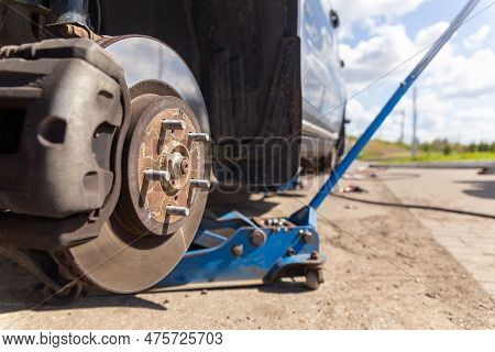 Car On Tire Mounting With Removed Wheel On Pneumatic Jack, Seasonal Tire Change, Car Service Concept