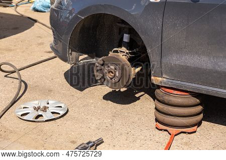 Car On Tire Mounting With Removed Wheel On Pneumatic Jack, Seasonal Tire Change, Car Service Concept