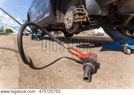 Car On Tire Mounting With Removed Wheel On Pneumatic Jack, Seasonal Tire Change, Car Service Concept