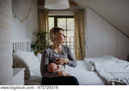 Mother Brestfeeding Her Little Newborn Baby In Their Bedrooom.