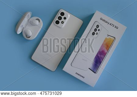 April 22, 2023 Ukraine City Kyiv Smartphone Samsung Galaxy A 73 With Headphones On A Colored Backgro