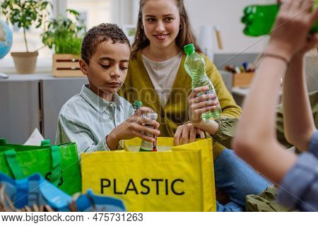 Children With Teacher Separating Rubish In To Three Bins.