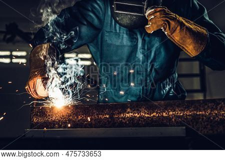 Metal Welder Working With Arc Welding Machine To Weld Steel At Factory While Wearing Safety Equipmen