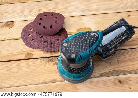 Round Sandpaper Discs And Orbital Sander. Wooden Background