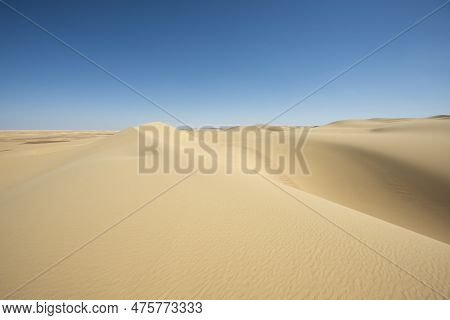 Landscape Scenic View Of Desolate Barren Western Desert In Egypt With Large Sand Dunes Against Blue 