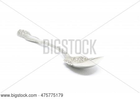 Ornate Antque Silver Spoon Photographed With A Shallow Depth Of Field On A Pure White Tablecloth.