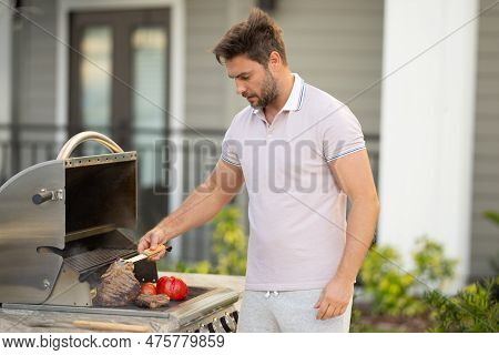 Barbecue Master. Middle Aged Hispanic Man In Apron For Barbecue. Roasting And Grilling Food. Man Hol
