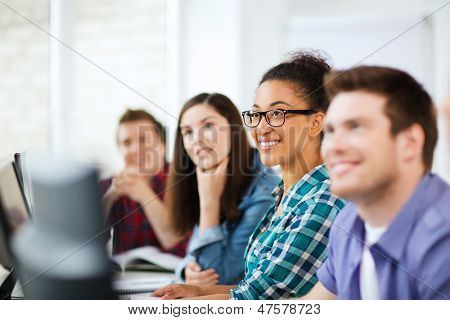 education concept - students with computers studying at school