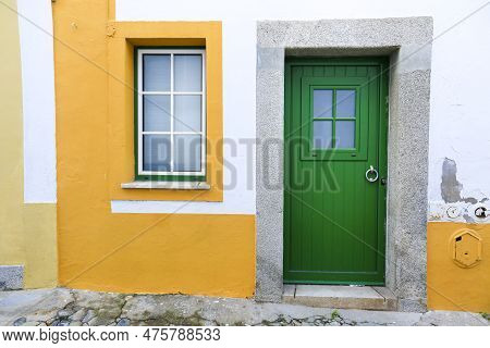 Typical Portuguese Facade With Green Wooden Door On Cobblestone Street In Evora Town, Portugal