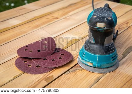Round Sandpaper Discs And Orbital Sander. Wooden Background