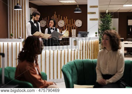 Hotel Team Reading Record Of Check In At Reception Counter, Providing Luxury Rooms For Accommodation
