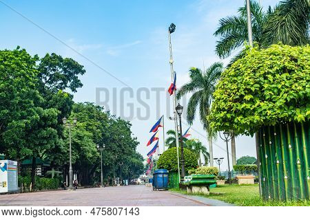 A Pathway With A Row Of Philippine Flags And Trees At The Rizal Park Along Taft Ave., Manila, Philip