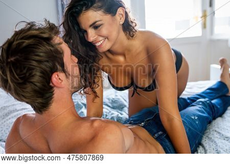 Sensual Young Couple Together In Bed. Happy Couple In Bedroom Enjoying Sensual Foreplay.