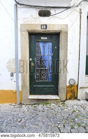 Evora, Portugal- October 10, 2022: Typical Portuguese Facade With Green Wooden Door On Cobblestone S