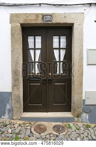 Evora, Portugal- October 10, 2022: Typical Portuguese Facade With Wooden Door On Cobblestone Street 