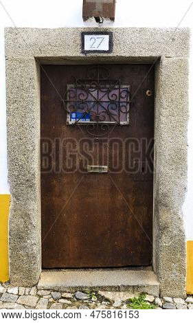 Evora, Portugal- October 10, 2022: Typical Portuguese Facade With Wooden Door On Cobblestone Street 