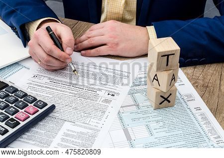 Businessman Filling W-4 Form With Pen, Calculator And Pc