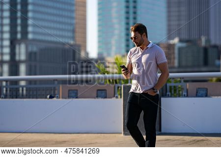 Young Handsome Man In Classik Polo T-shirt Chatting On Phone On The Street. Handsome Confident Styli