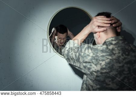 Stressed Military Veteran Suffering From Post Traumatic Stress Disorder Near Mirror At Home At Night