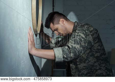 Side View Of Soldier With Post Traumatic Stress Disorder Suffering From Flashbacks At Home At Night.