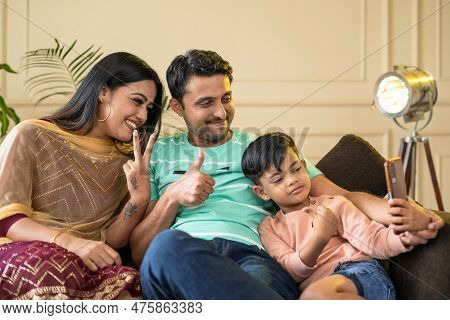 Happy Realxed Family With Kid Taking Selfie On Mobile Phone While Sitting On Sofa At Home - Concepts