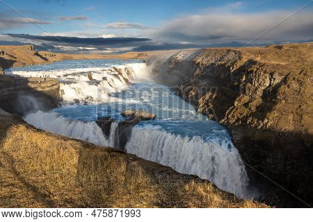 Famous Part Of The Golden Circle. Two Cascades Of The Gullfoss Waterfall, Surrounded By Cliffs. Gold