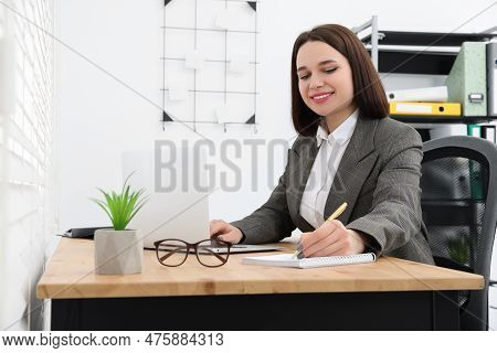 Happy Young Intern Working At Table In Modern Office