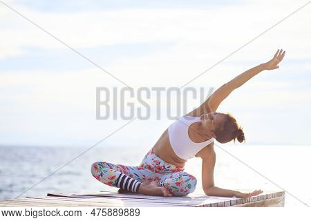 Woman Doing Yoga On Beach Pier Against Brightness Sun Light