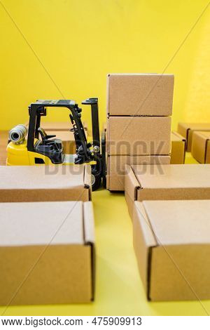 Warehouse With Cardboard Kraft Boxes And A Forklift Truck. Cargo Sorting And Product Delivery Concep