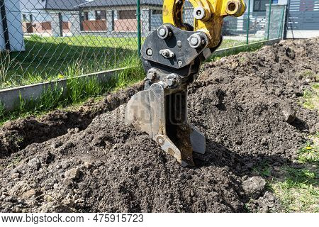Mini Digger Digging A Hole In The Garden Along The Fence To The Drainage Pipes.