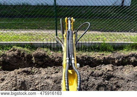 Mini Digger Digging A Hole In The Garden Along The Fence To The Drainage Pipes.