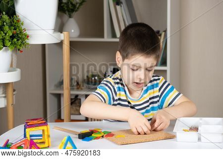 A Preschool Child Plays With A Mosaic, Builds Figures On A Board, Hammering Nails With A Hammer On M